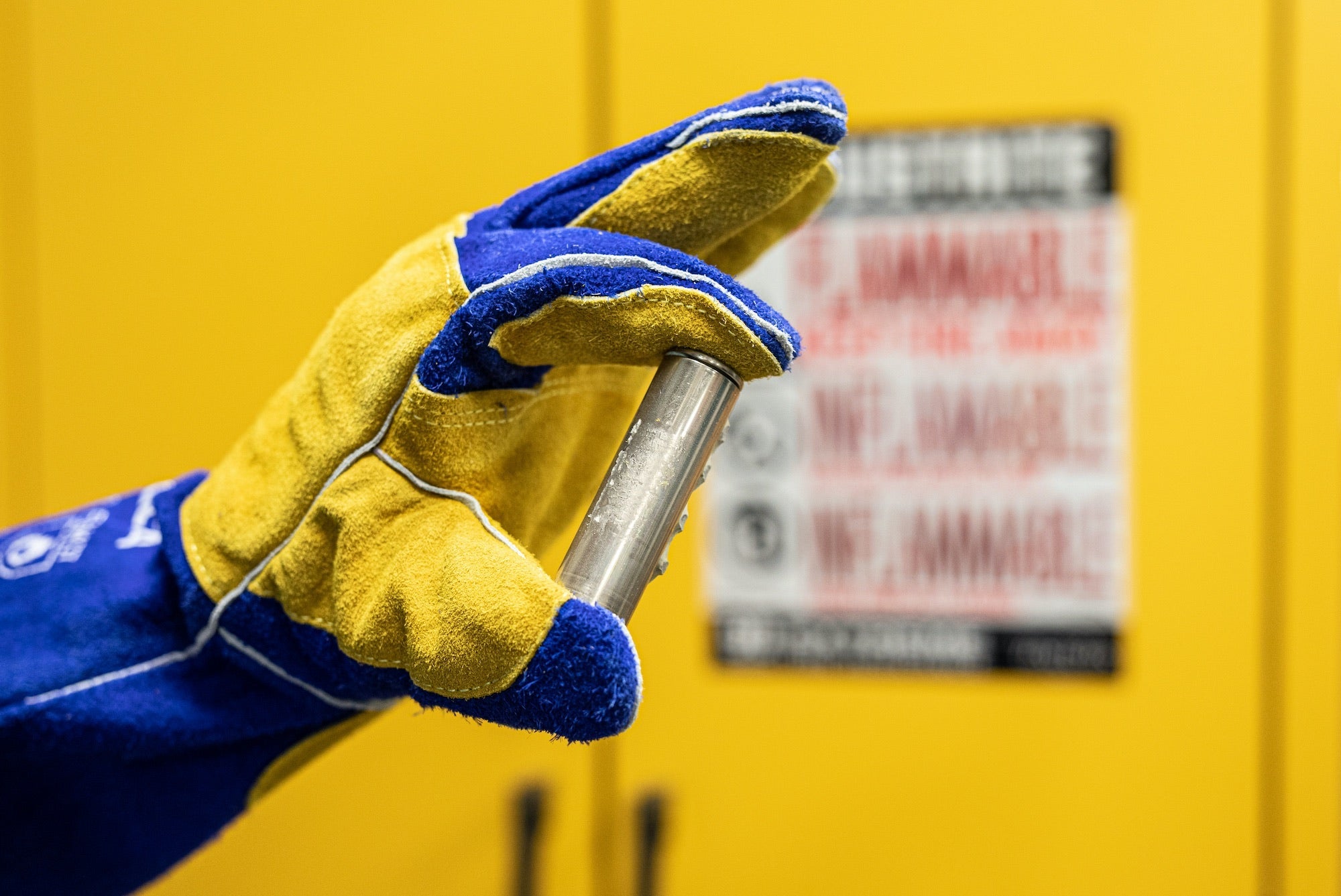 Photo of a gloved hand holding a single battery cell in a SLAC battery lab.