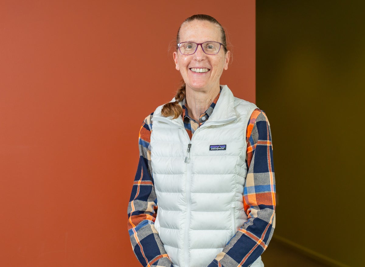 SLAC's Kathleen Ratcliffe poses for a portrait in the corner between two brightly colored walls in one of the lab's buildings. 