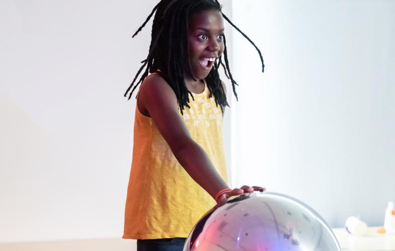 A young camper engages with a Van der Graaf generator exhibit at Core science institute
