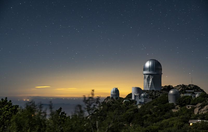 A telescope building sits atop a mountain in twilight.