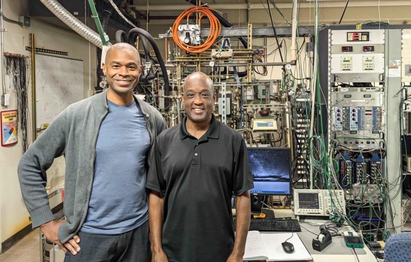 Fred Lacy and Kolo Wamba stand in front experimental equipment.