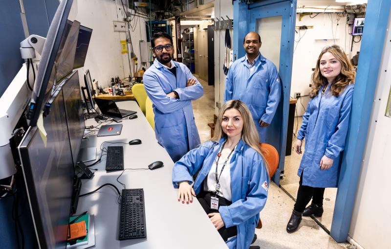 Group of SLAC workers in front of computer monitors smiling at the camera.