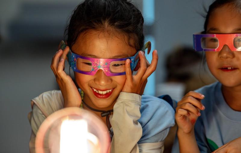 A child looks at a light bulb while wearing glasses with diffraction lenses