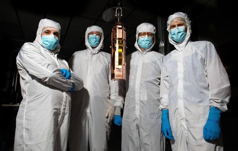 SuperCDMS team members posing with a detector tower.