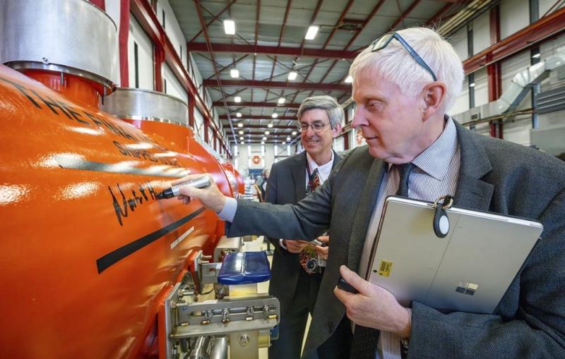 Fermilab Director Norbert Holtkamp signs a cryomodule while SLAC Director John Sarrao looks on.