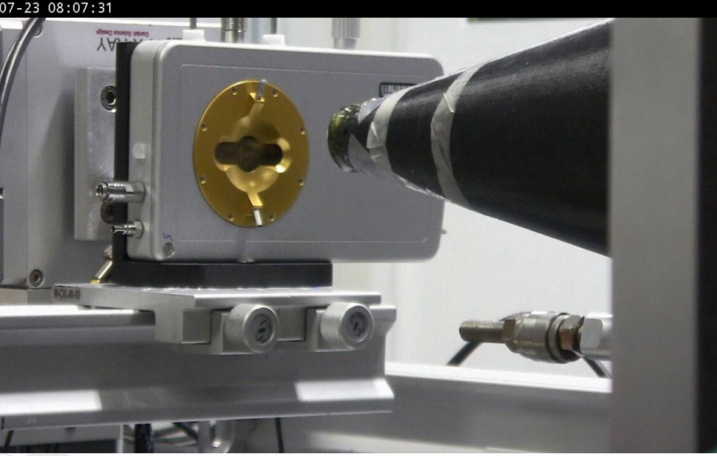 An X-ray beam line guide points toward a gold-colored piece of laboratory equipment.