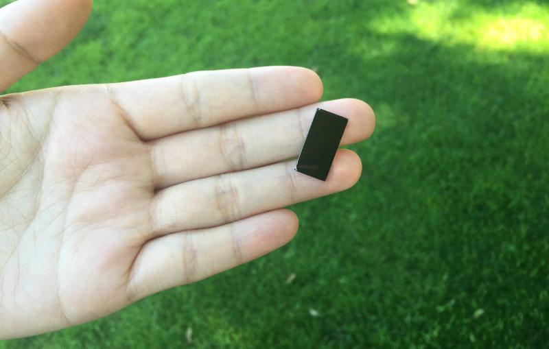 A researcher holds a tiny device that uses sunlight to disinfect water.