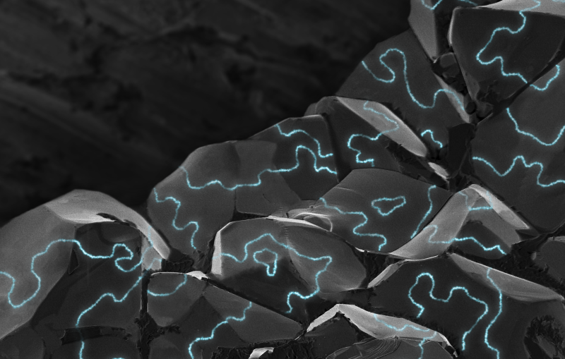 An illustration of electrically conductive areas (blue) along the boundaries of tiny magnetic regions, or domains, in chunky grains of a material that normally doesn’t conduct electricity.
