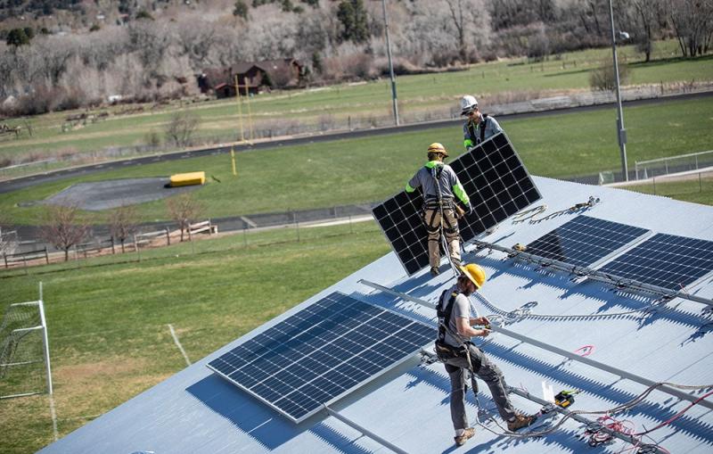 Workers install solar panels on a home