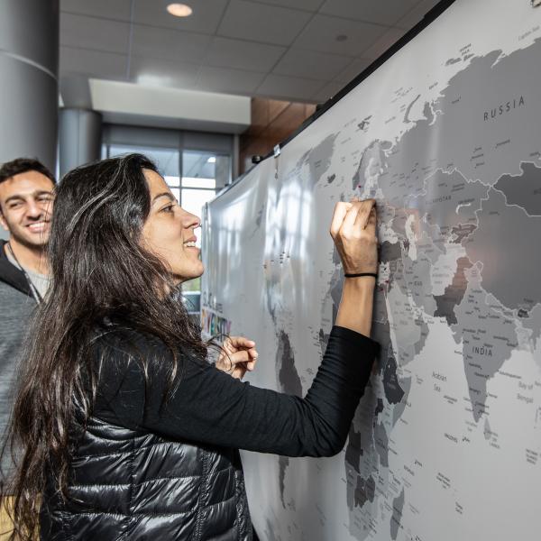 Margaret Ghaly puts a pin in one of the two countries she calls home on the SLAC Celebrates Diversity Around the World Map on display at the 2019 SLAC Holiday Party.
