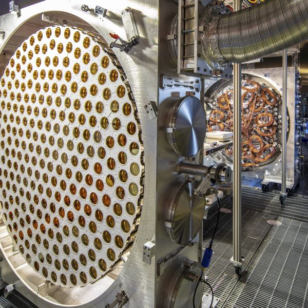 Large detector component filled with dozens of gold-colored photosensors, with cables and additional scientific equipment visible in the background.