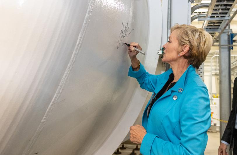 Secretary of Energy Jennifer M. Granholm adds her signature to one of the LCLS-II cyroplant's cold boxes