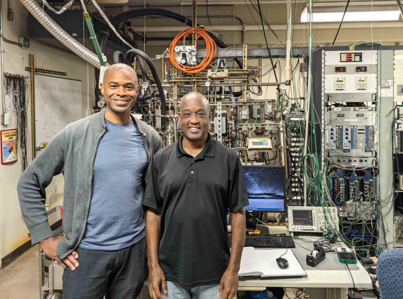 Fred Lacy and Kolo Wamba stand in front experimental equipment.