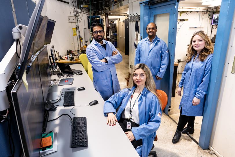 Group of SLAC workers in front of computer monitors smiling at the camera.