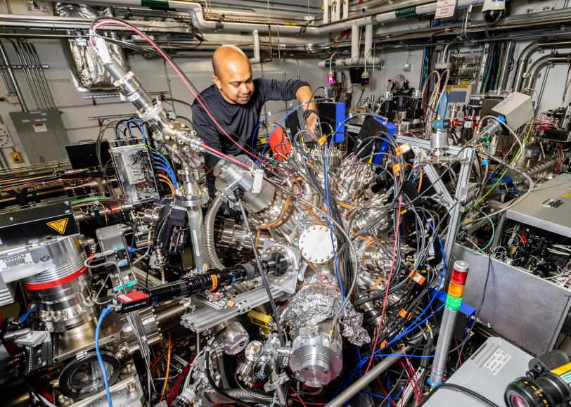 An individual working on a detailed and busy setup of interconnected equipment in a technology-filled workspace.