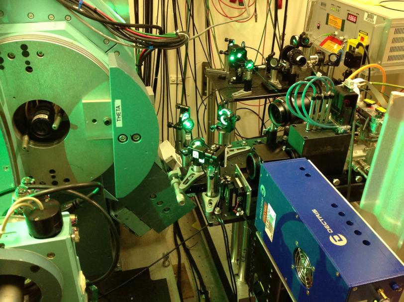 Photo - Green laser light is visible in an experimental setup at SLAC's SSRL. Infared laser light was "frequency-doubled" to produce this green laser light. The large apparatus on the left is an X-ray diffractometer that was used to align the sample.