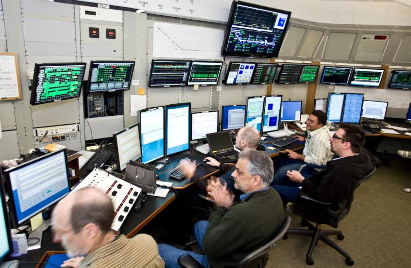 Image - Several members of the commissioning team work in the Main Control Center to turn on the LCLS laser (2009 photo). Paul Emma, center, led the effort to turn on the laser. (Brad Plummer)