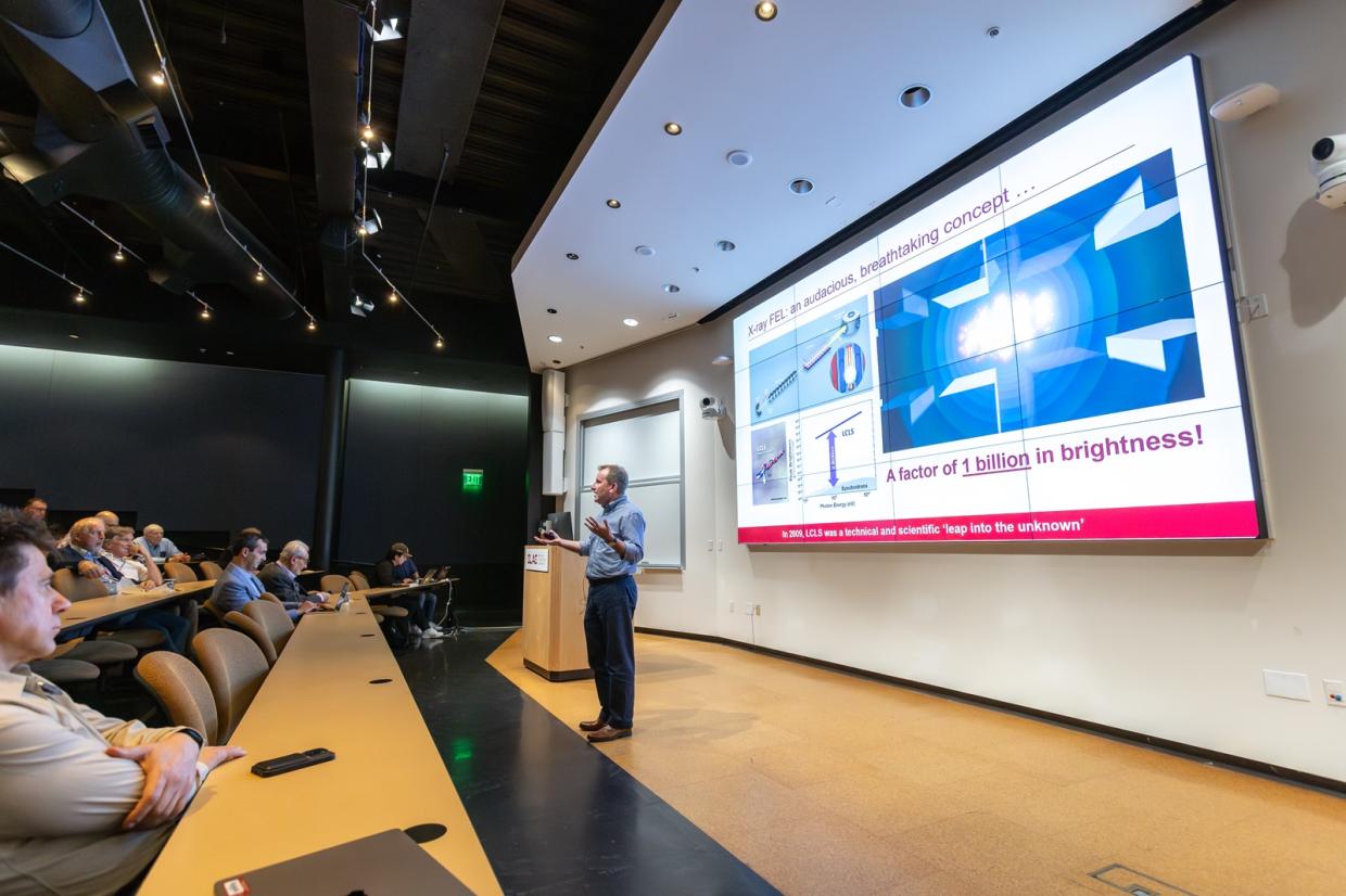 A presenter speaks in an auditorium.