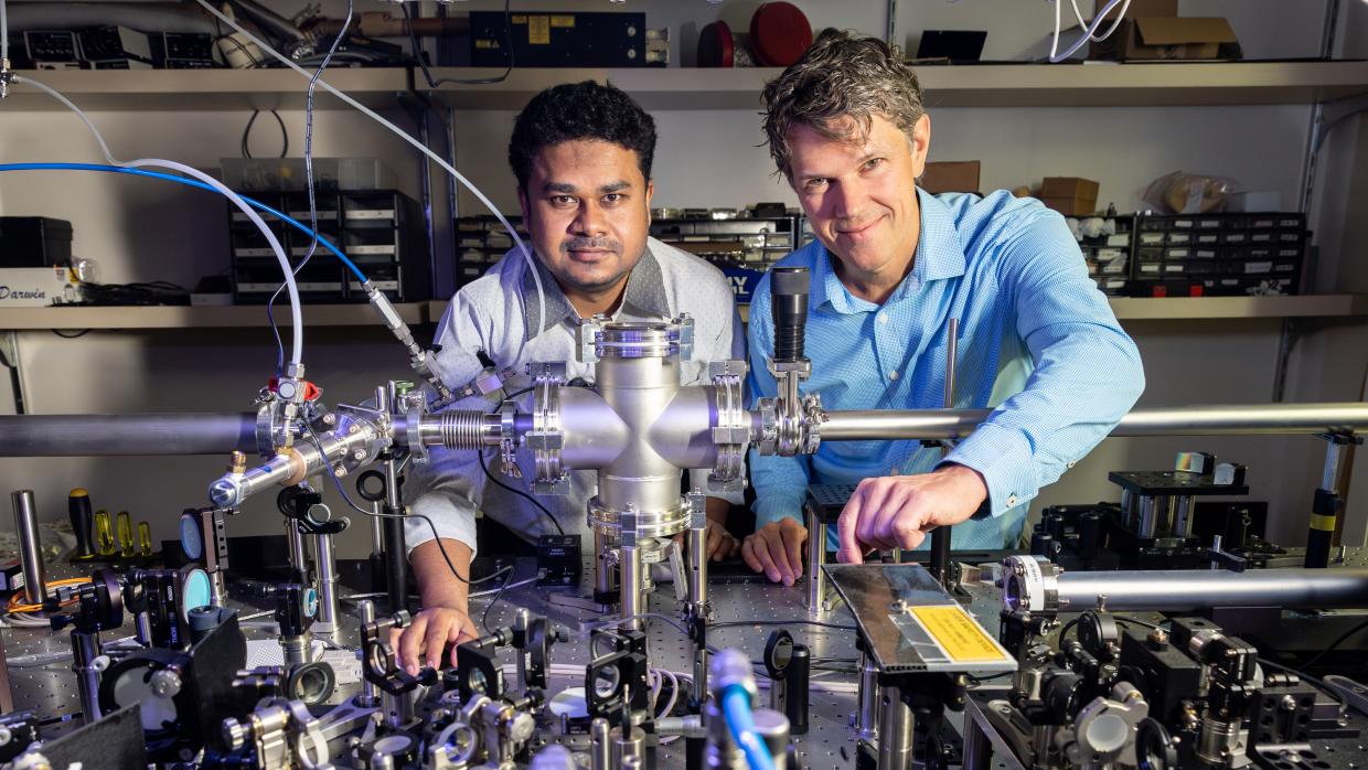 Two smiling scientists standing near equipment used to study ultrafast processes with SLAC’s X-ray laser, lightly touching components while facing the camera.