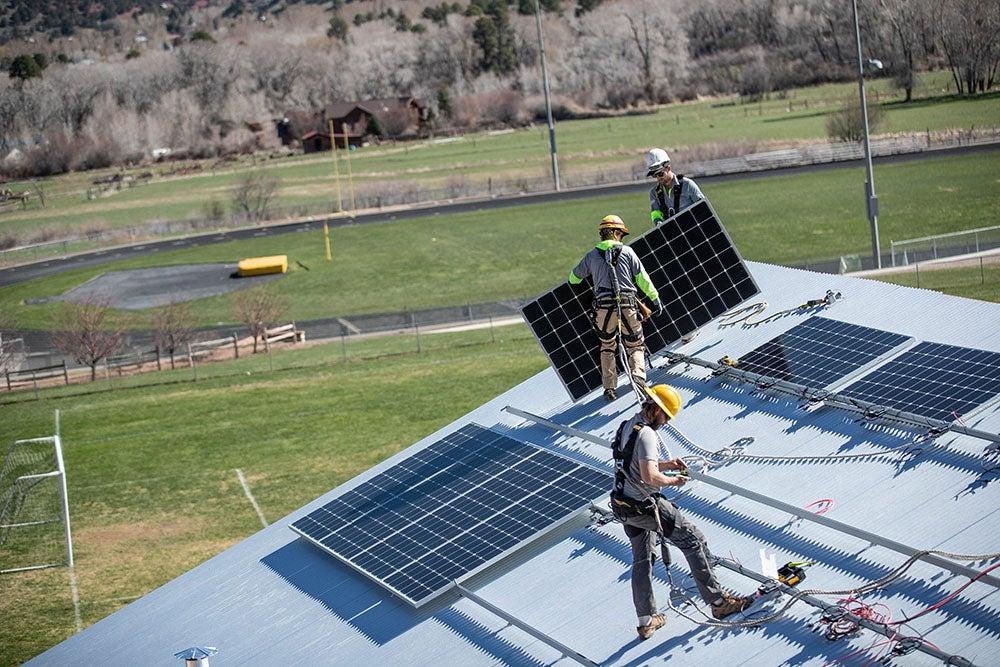 Workers install solar panels on a home