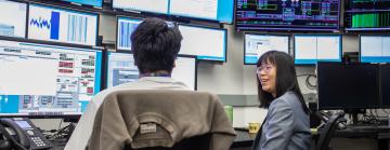 Wan-Lin Hu is seen talking with talks with accelerator systems operator Kabir Lubana in the lab’s main Accelerator Control Room. 