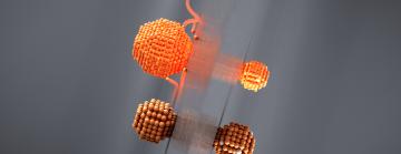 Clustered orange spheres float beside a reflective gray plane, casting soft glows and reflections amid swirling ribbon-like streaks. 