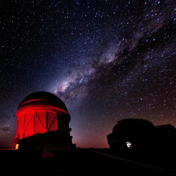 An observatory bathed in red light against a starry night sky