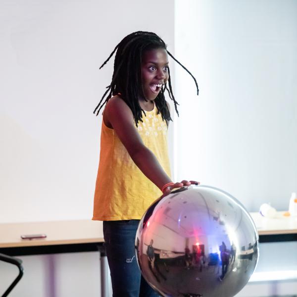 A young camper engages with a Van der Graaf generator exhibit at Core science institute