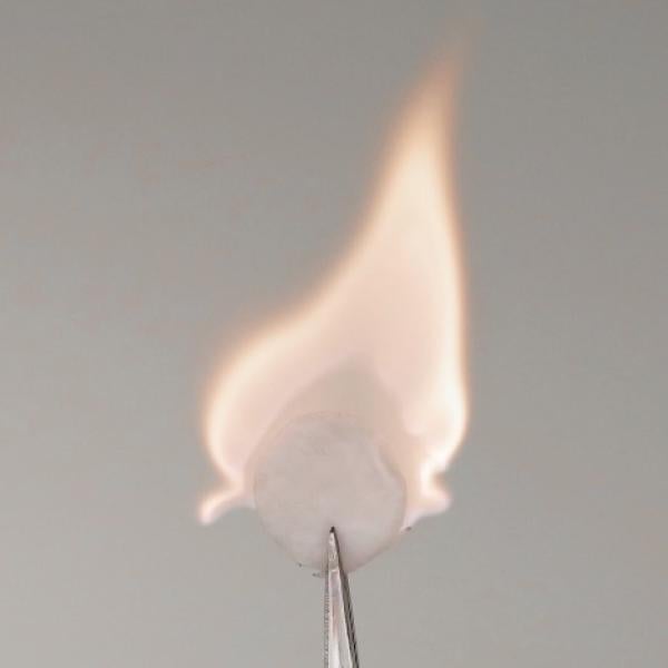 A white disc of battery material catches fire.
