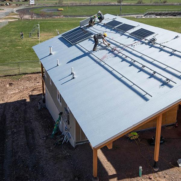 Aerial image of workers installing solar panels on a home.