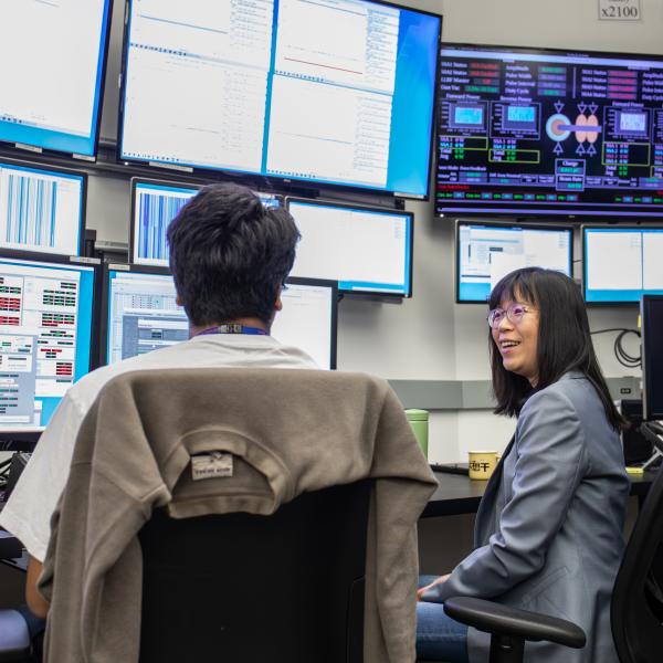 Wan-Lin Hu is seen talking with talks with accelerator systems operator Kabir Lubana in the lab’s main Accelerator Control Room. 