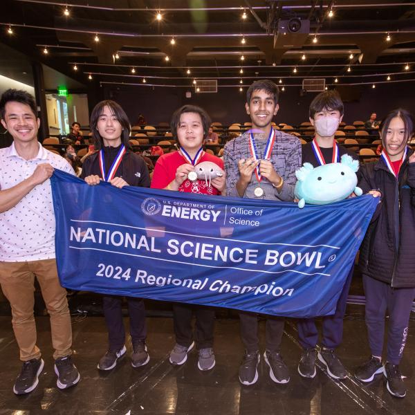 High school students hold up a blue National Science Bowl banner.