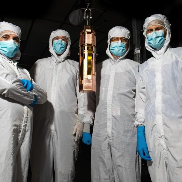 SuperCDMS team members posing with a detector tower.