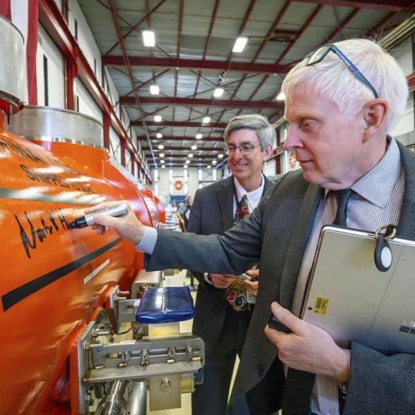 Fermilab Director Norbert Holtkamp signs a cryomodule while SLAC Director John Sarrao looks on.