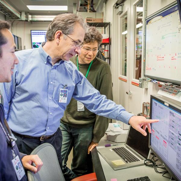 Photo - Nicholas Sauter, middle, points to a monitor during an experiment this month at SLAC's Linac Coherent Light Source X-ray laser.