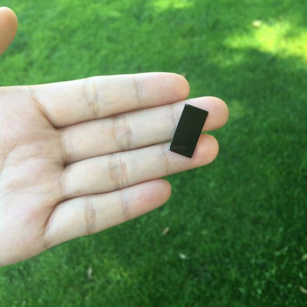 A researcher holds a tiny device that uses sunlight to disinfect water.