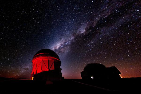 An observatory bathed in red light against a starry night sky